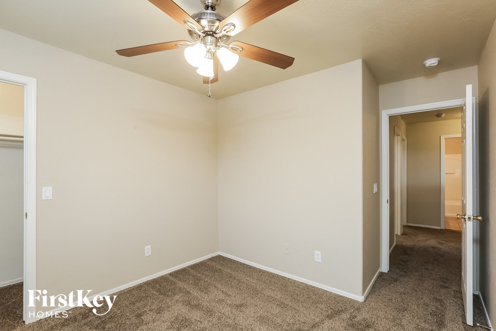 the living room of an empty home with a ceiling fan