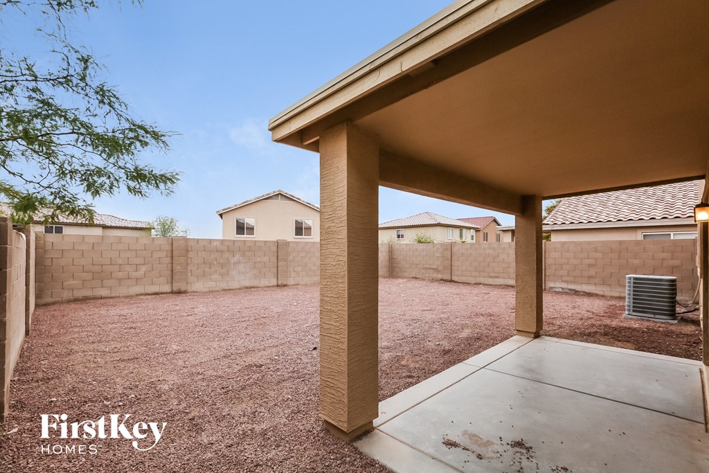 the backyard of a home with a patio and a brick wall
