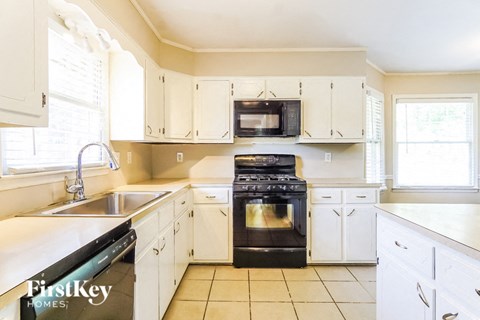 a large kitchen with white cabinets and black appliances