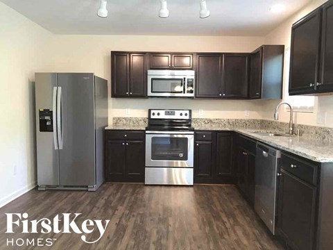 A kitchen with a refrigerator, oven, microwave, and cabinets.