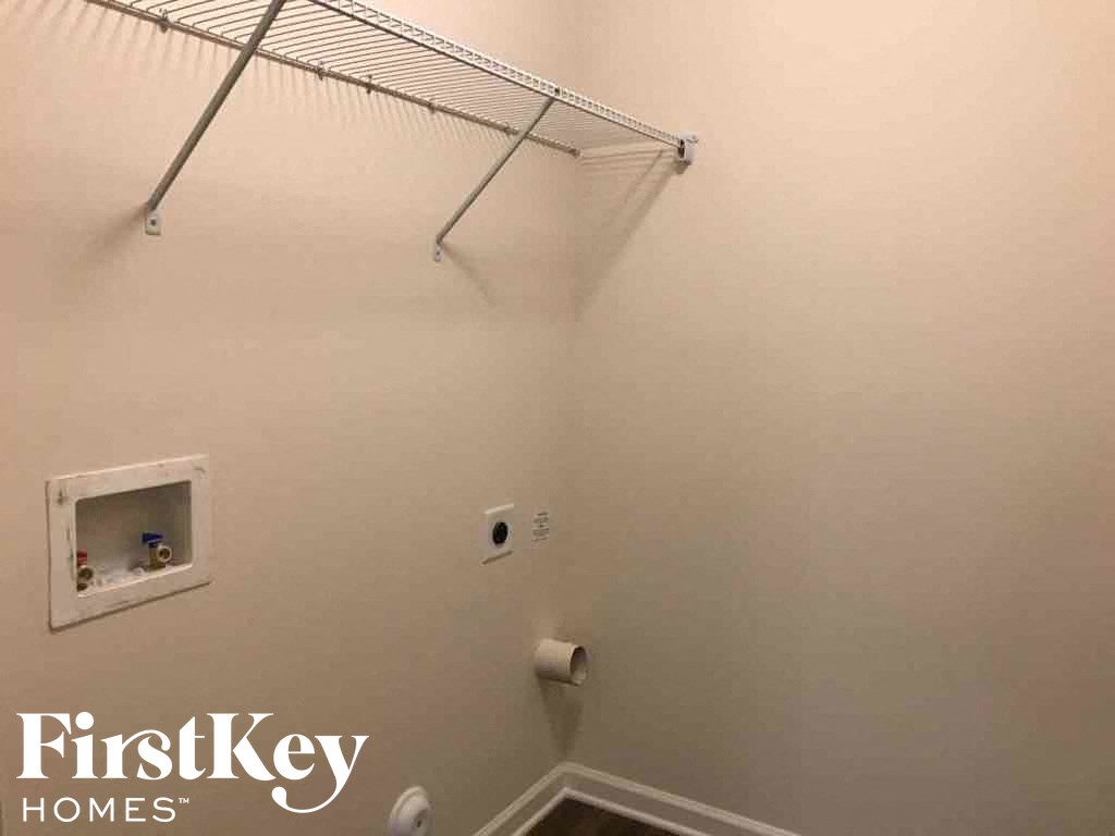 A white wall with a small shelf and a towel rack.