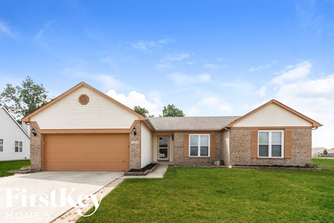 a brick house with a lawn and a driveway