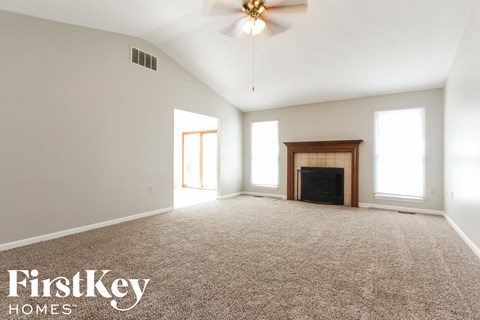 an empty living room with a fireplace and a ceiling fan