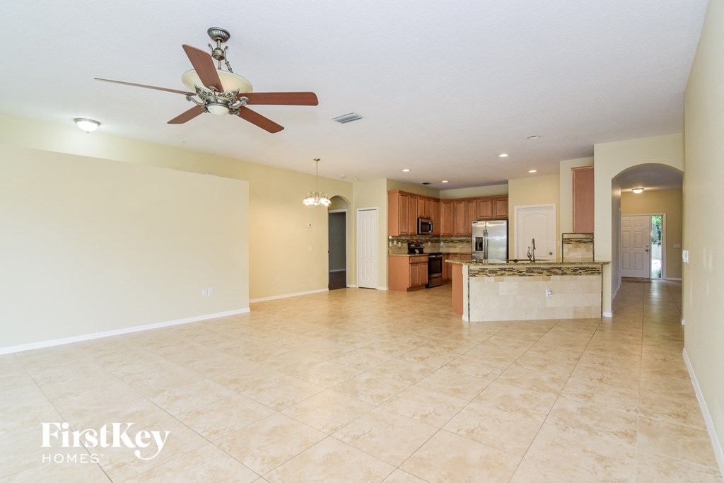 A spacious kitchen and living room with a fan on the ceiling.