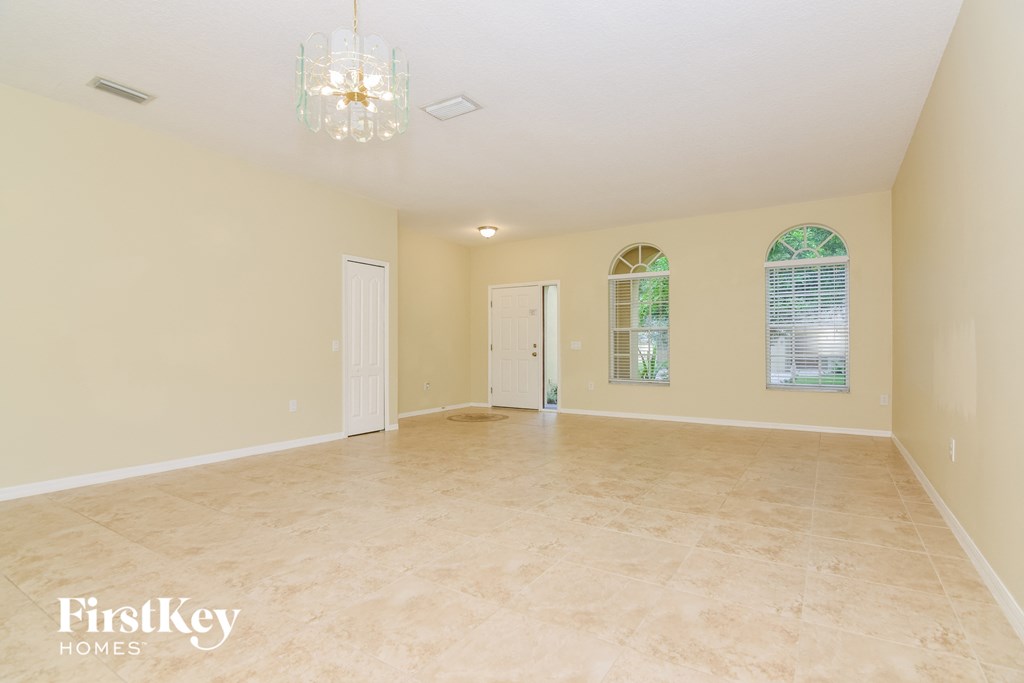 A spacious room with a chandelier and arched windows.