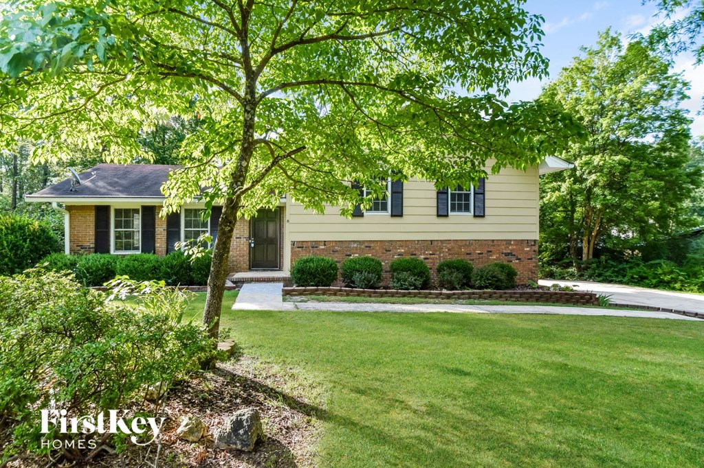 a home with a lawn and a tree in front of it