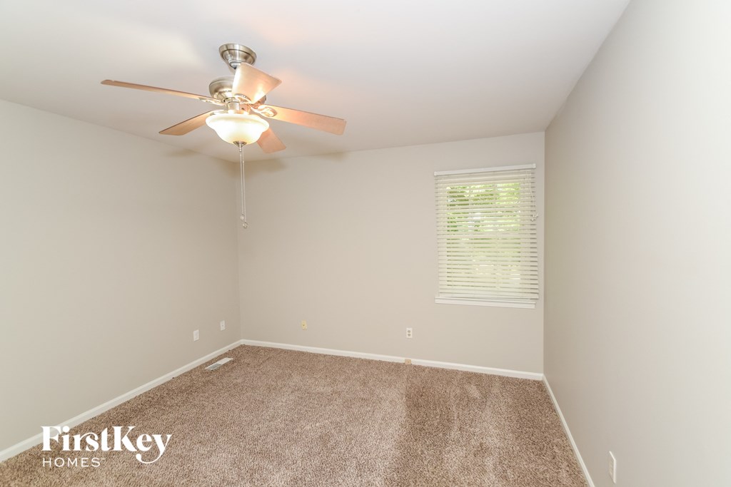 a bedroom with a ceiling fan and a carpet