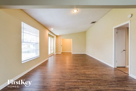 an empty living room with wood flooring and a large window