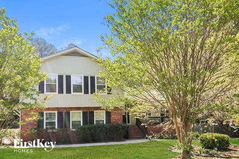 a house with a lawn and trees in front of it