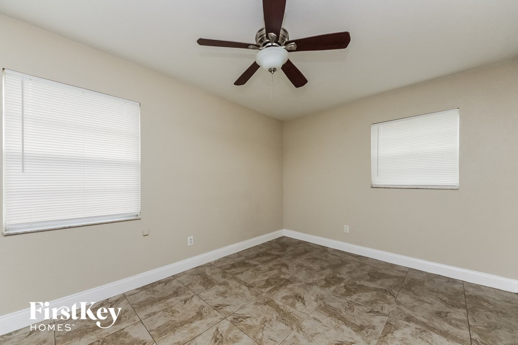 the bedroom has a large window and a ceiling fan