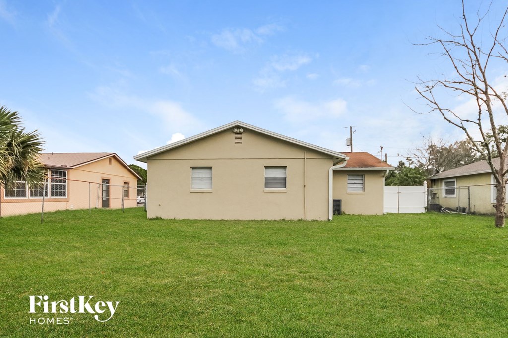 a beige house in a grassy yard with some houses