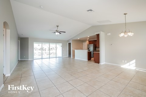 A spacious living room with a ceiling fan and a chandelier.
