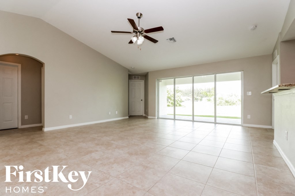 A spacious room with a ceiling fan and sliding glass doors.