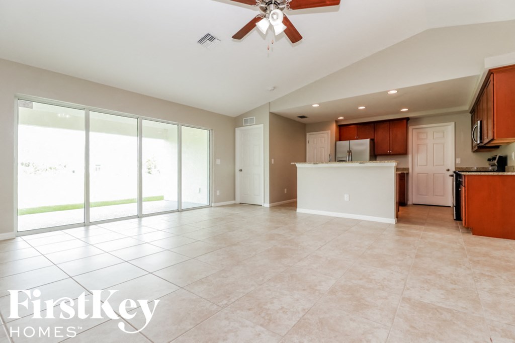 A spacious kitchen and living room with a ceiling fan and sliding glass doors.