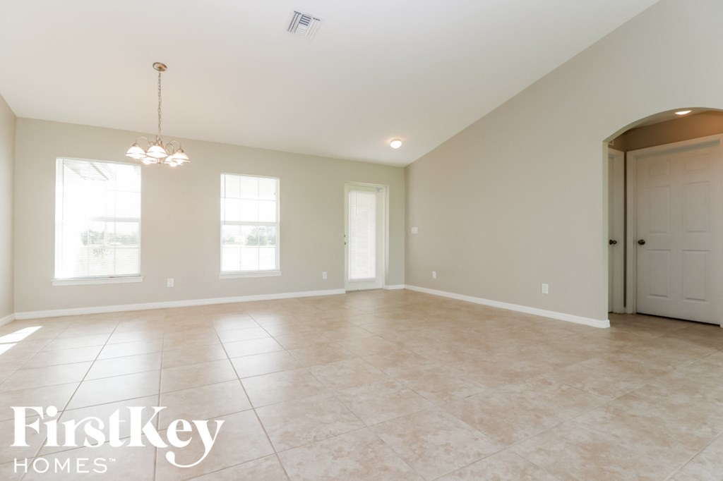 A spacious room with a chandelier and a door on the right side.