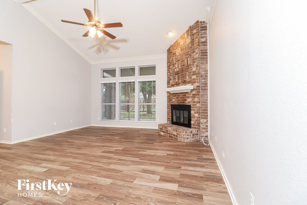 a living room with a brick fireplace and a ceiling fan