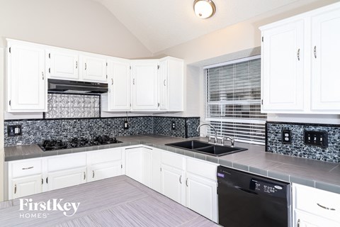 a kitchen with white cabinets and black counters and a sink
