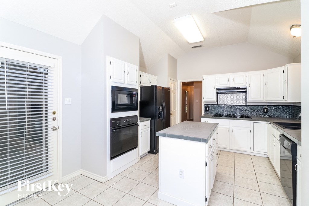 a kitchen with white cabinets and black appliances