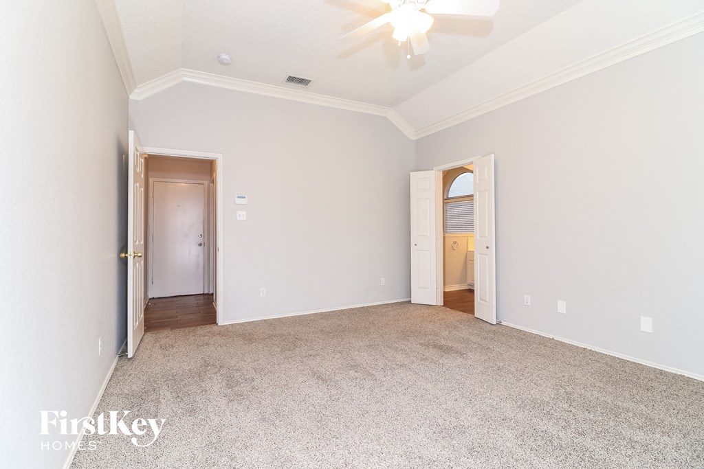 a bedroom with white walls and carpet and a door to a hallway