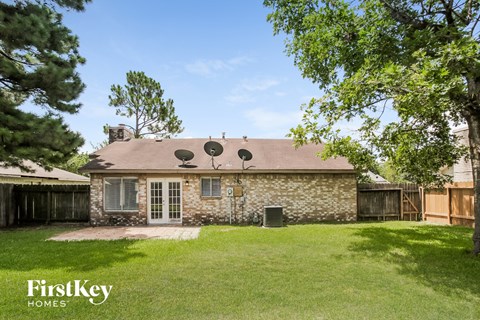 a backyard with a stone house and a yard with grass and trees