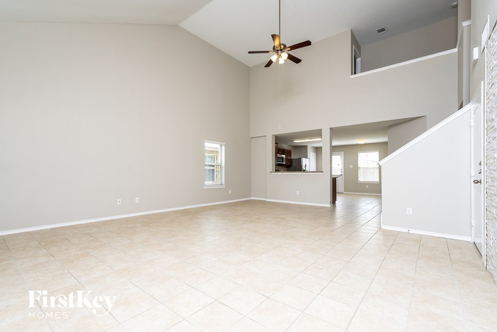 an empty living room with a ceiling fan and a tile floor
