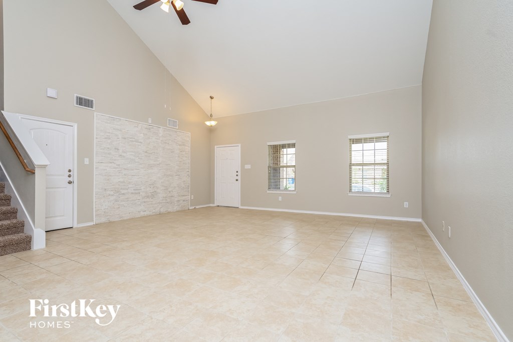 an empty living room with a staircase and a tile floor