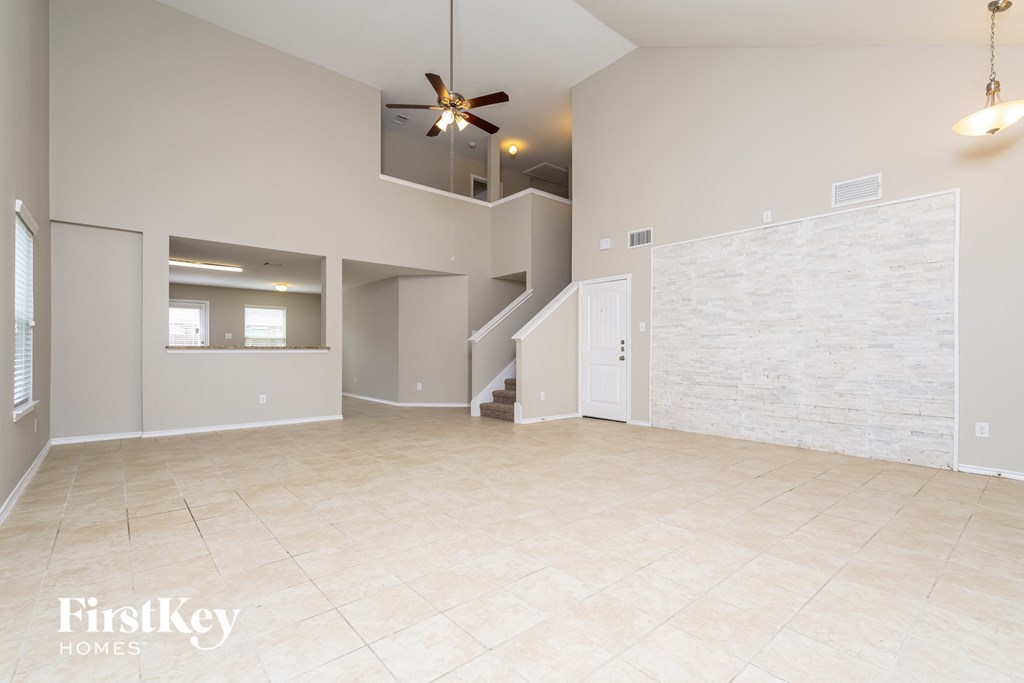 an empty living room with a staircase and a tile floor