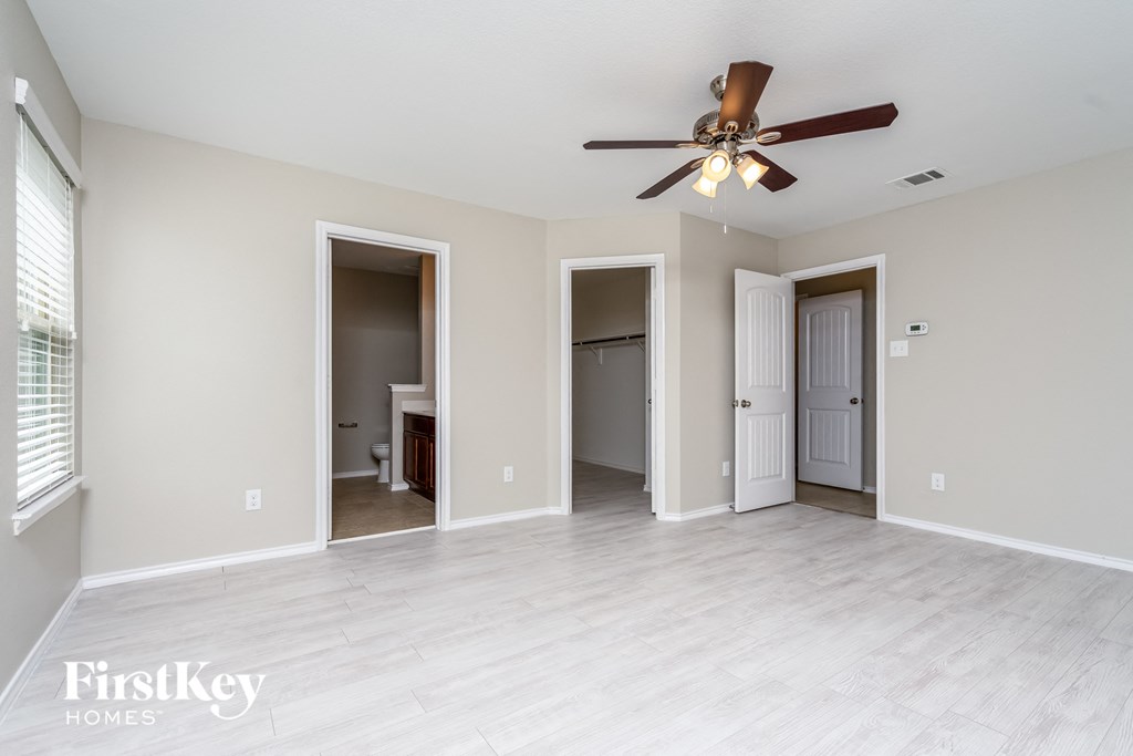 an empty living room with a ceiling fan and a door to a bathroom