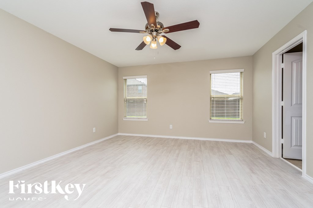 an empty living room with a ceiling fan and a window