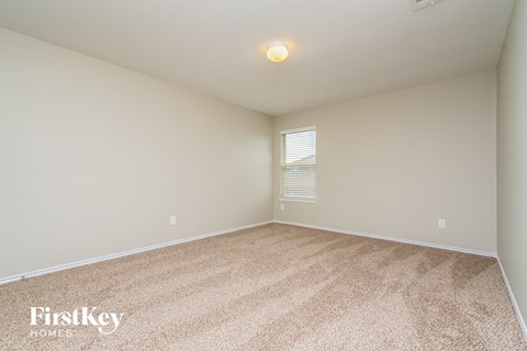 a spacious living room with beige carpet and a window