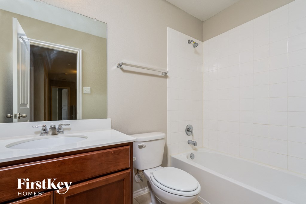 a bathroom with a toilet sink and tub and a mirror