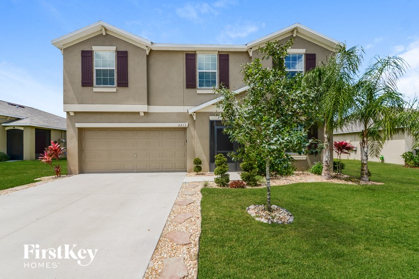 a beige house with a garage and a palm tree