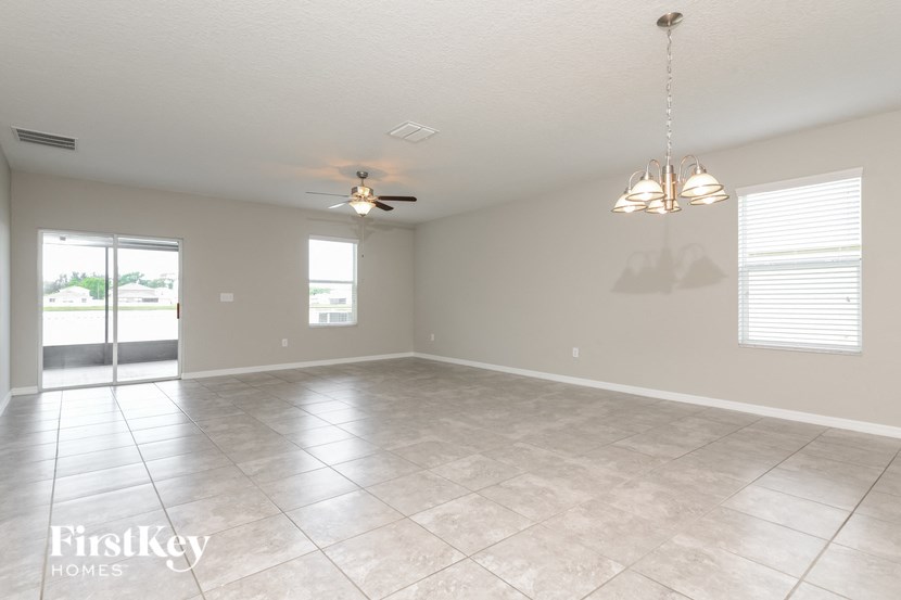 an empty living room with a ceiling fan and tile floor