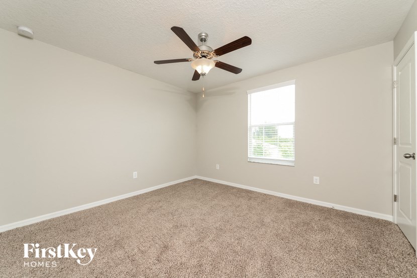 an empty room with a ceiling fan and a window