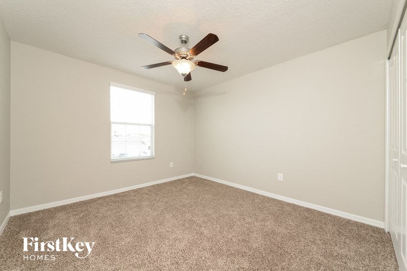 an empty room with a ceiling fan and a window