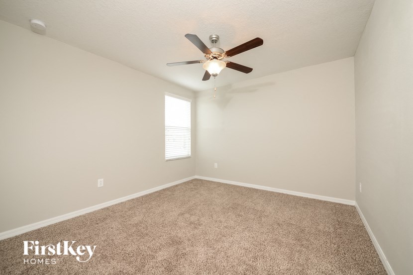 an empty room with a ceiling fan and a window