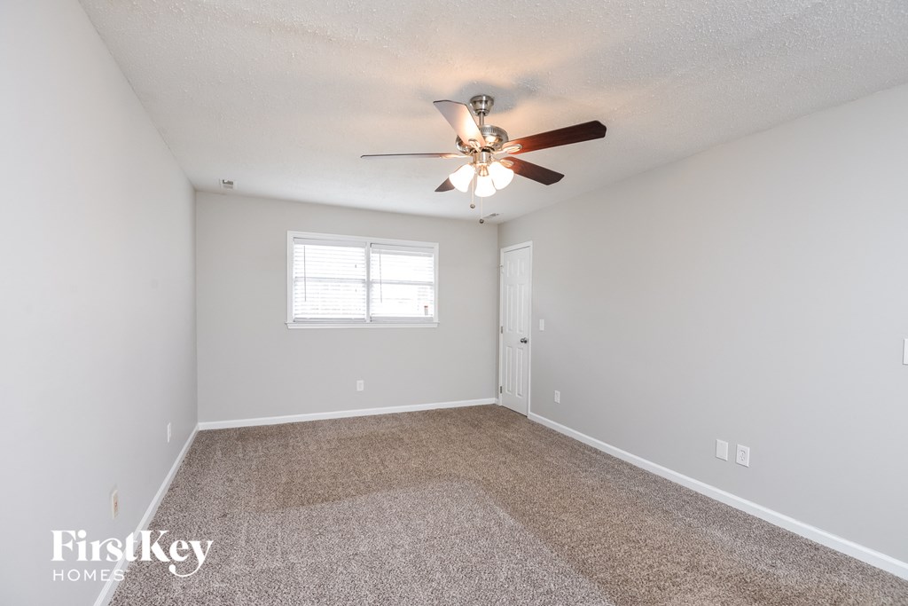 the spacious living room with ceiling fan and carpet