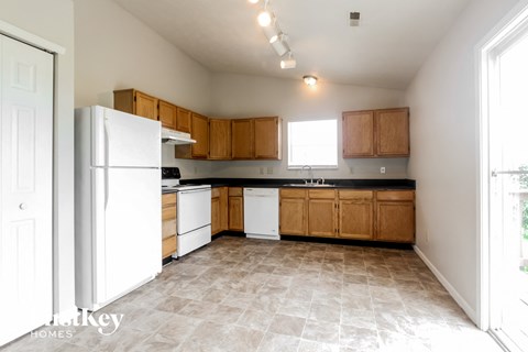 an empty kitchen with white appliances and wooden cabinets
