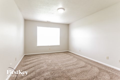a spacious room with carpet and a window