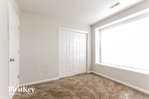 a bedroom with carpet and a window and a white door