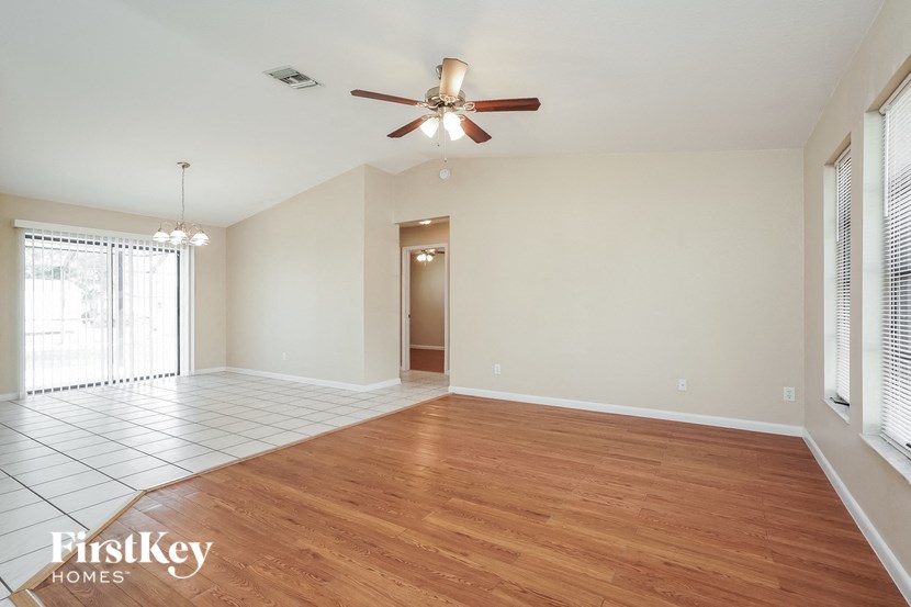 A spacious room with wooden floors and a ceiling fan.