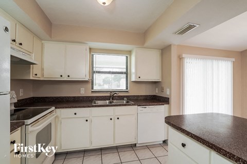A kitchen with white cabinets and a brown countertop.