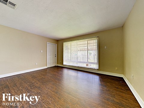 A room with wooden floors and a window with blinds.