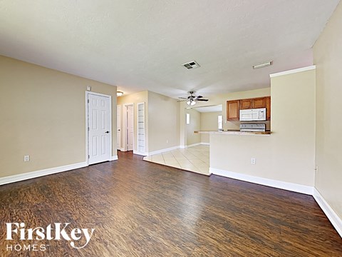 A spacious room with wood flooring and a ceiling fan.