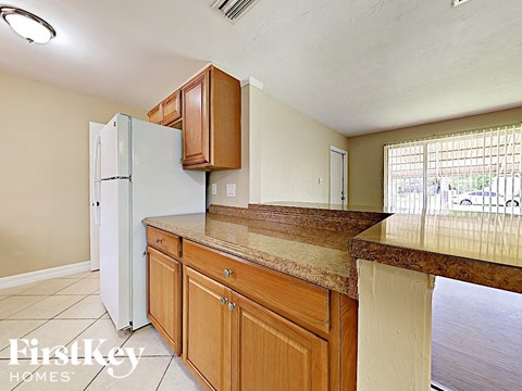 A kitchen with a white refrigerator and wooden cabinets.