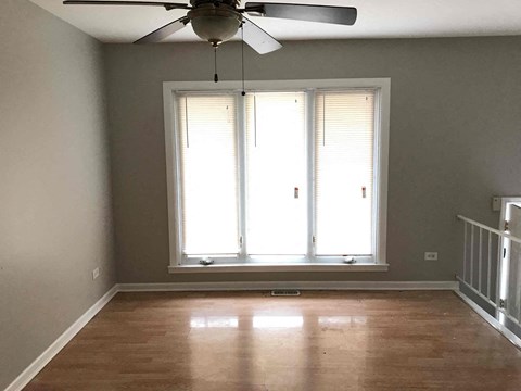 a living room with a large window and a ceiling fan