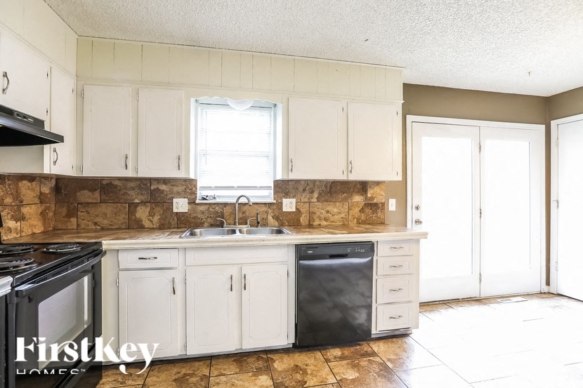 A kitchen with a stove, sink, and cabinets.