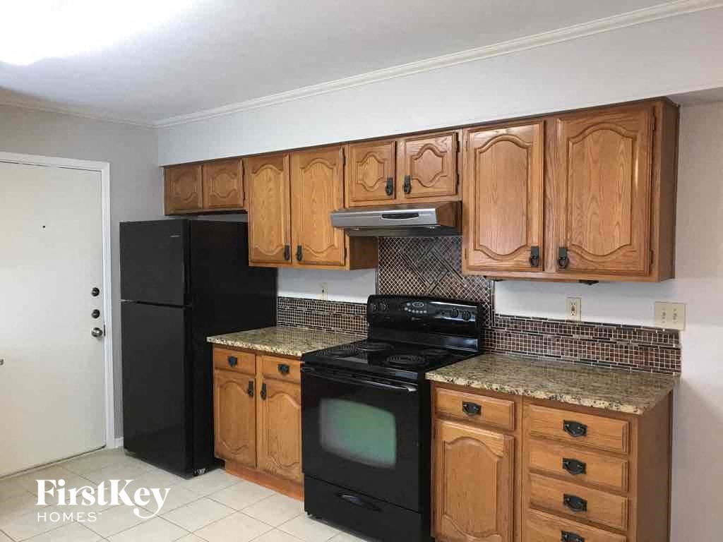 a kitchen with wooden cabinets and a black refrigerator
