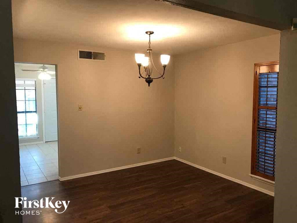 an empty dining room with a wooden floor and a chandelier