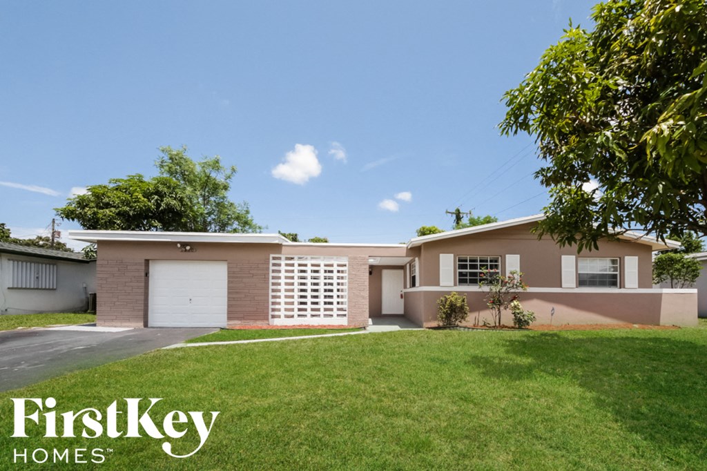 a pink house with a lawn and a white garage door